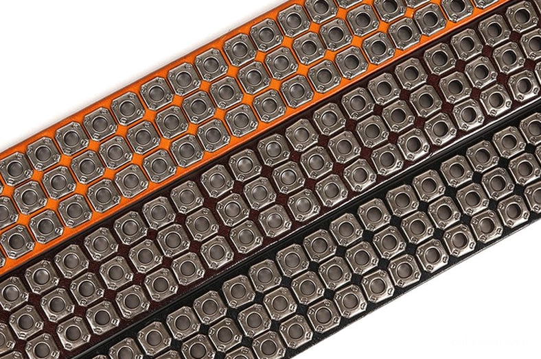 Close-up detail of square metal grommets on black gothic studded leather belt in uniform rows