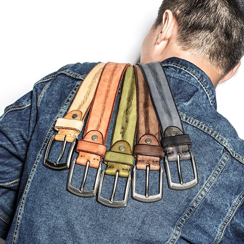 Multiple vintage leather gothic belts displayed on denim jacket worn by male model from back view, showcasing real-world styling and alternative fashion application