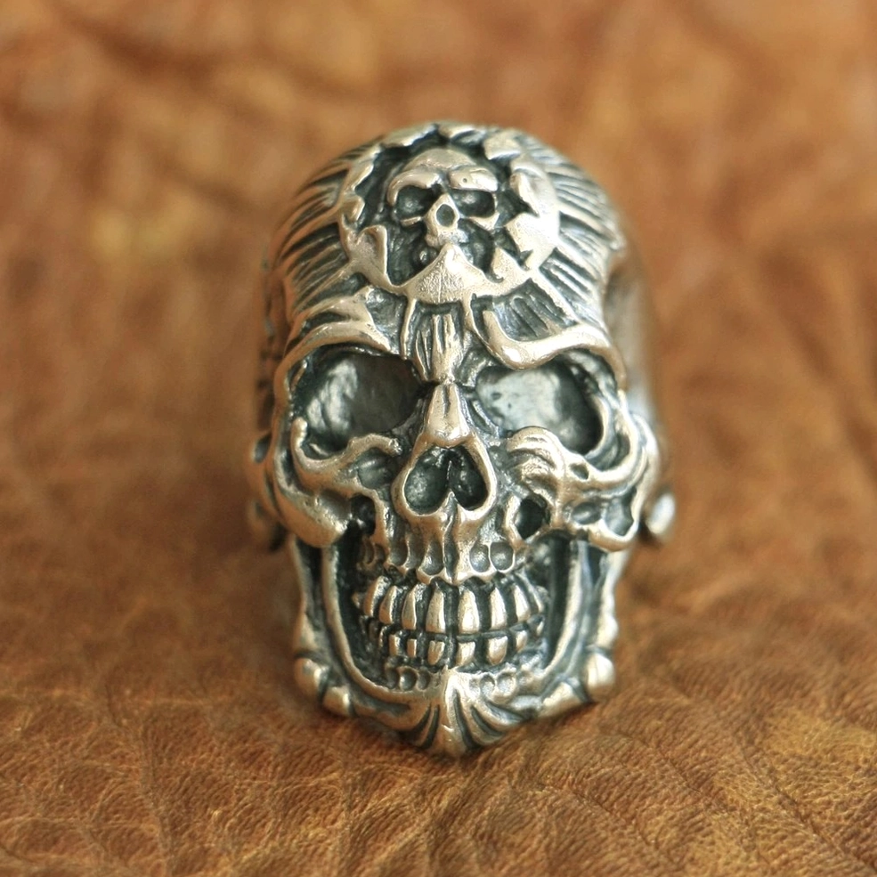 Biker gothic skull ring flat lay on brown leather background showcasing antique silver finish