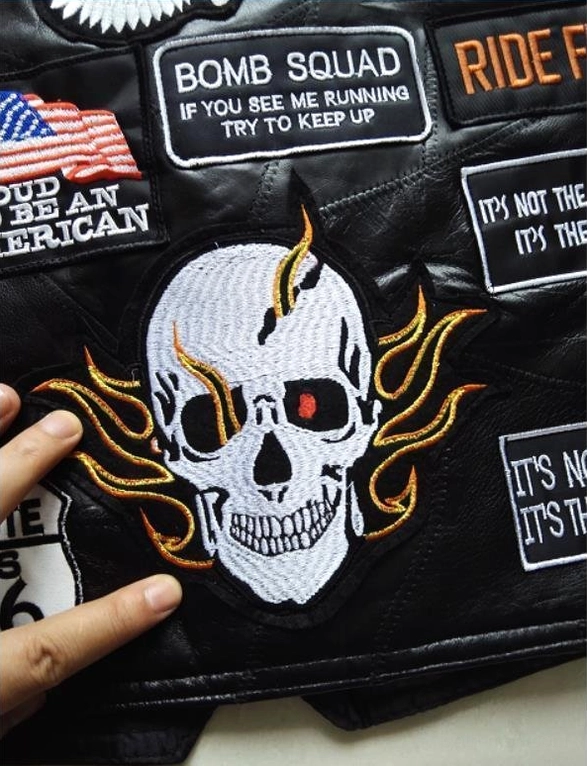 Detailed view of embroidered patches on gothic biker vest flame skull bomb squad insignia