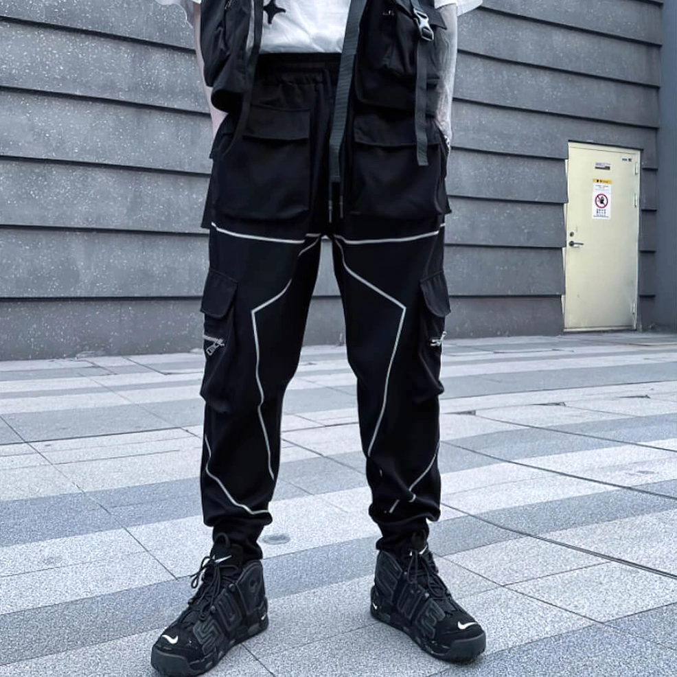 Black cargo pants outdoor street style front three-quarter view with reflective piping on industrial concrete
