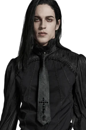 Black jacquard gothic necktie with cross studs worn by male model, front half-body studio shot showcasing coffin charm detail and woven paisley pattern