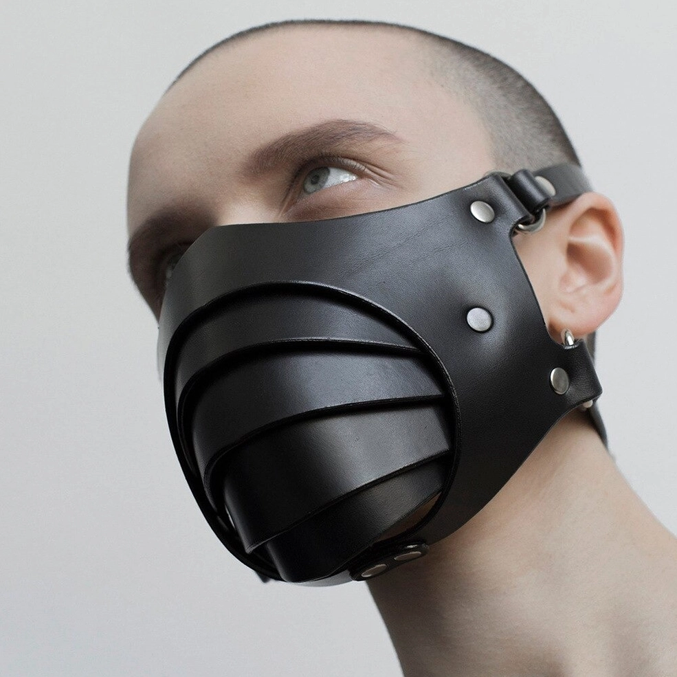 Black leather gothic face mask front view on male model showcasing metal rivet fasteners and adjustable fit