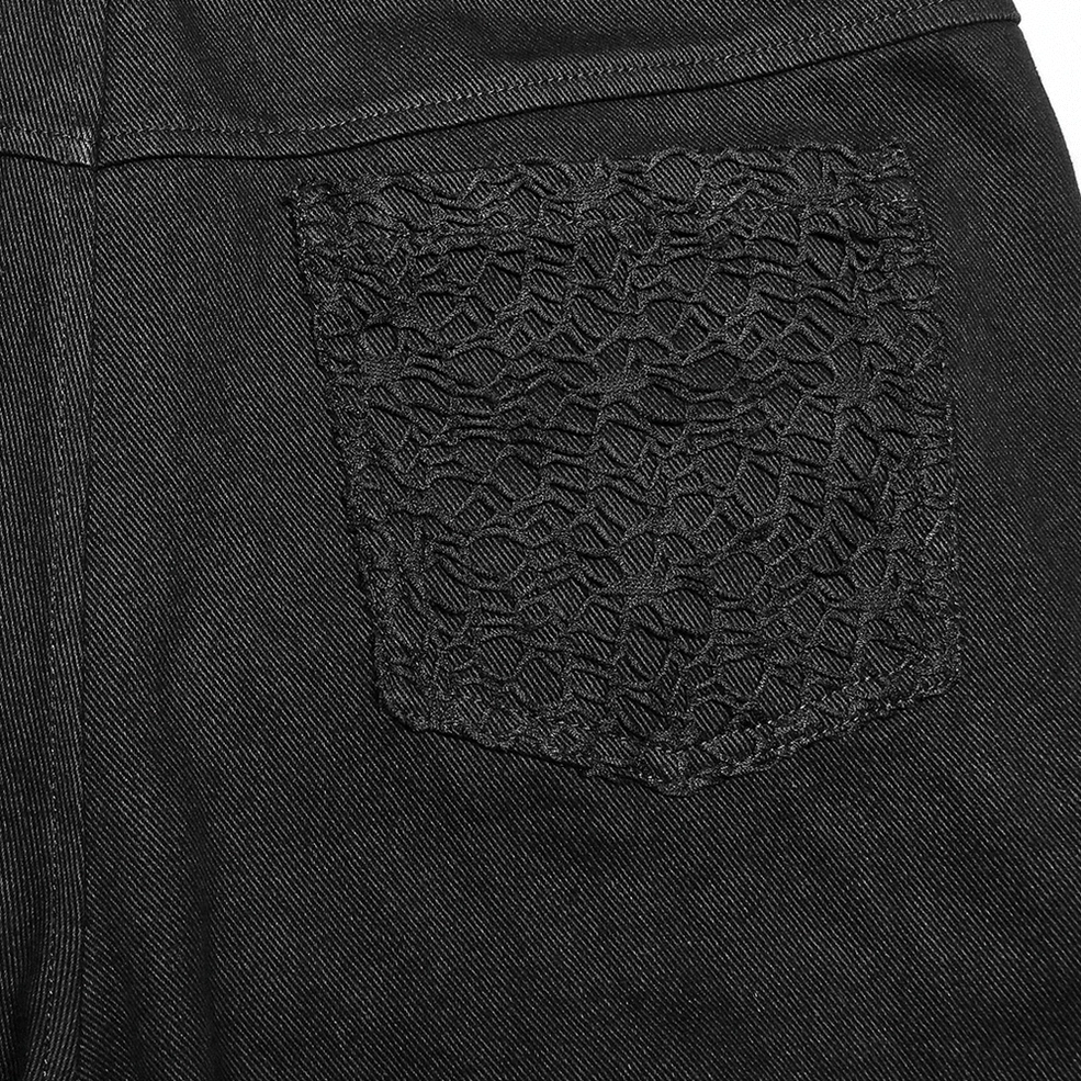 Detail of embroidered lace pocket panel on black gothic trousers with denim weave