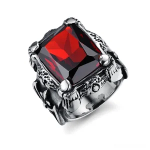 Gothic blood red square zircon ring with carved metal band and four-claw tension setting, 3/4 oblique view showing crimson faceted gemstone and ornate stainless steel frame