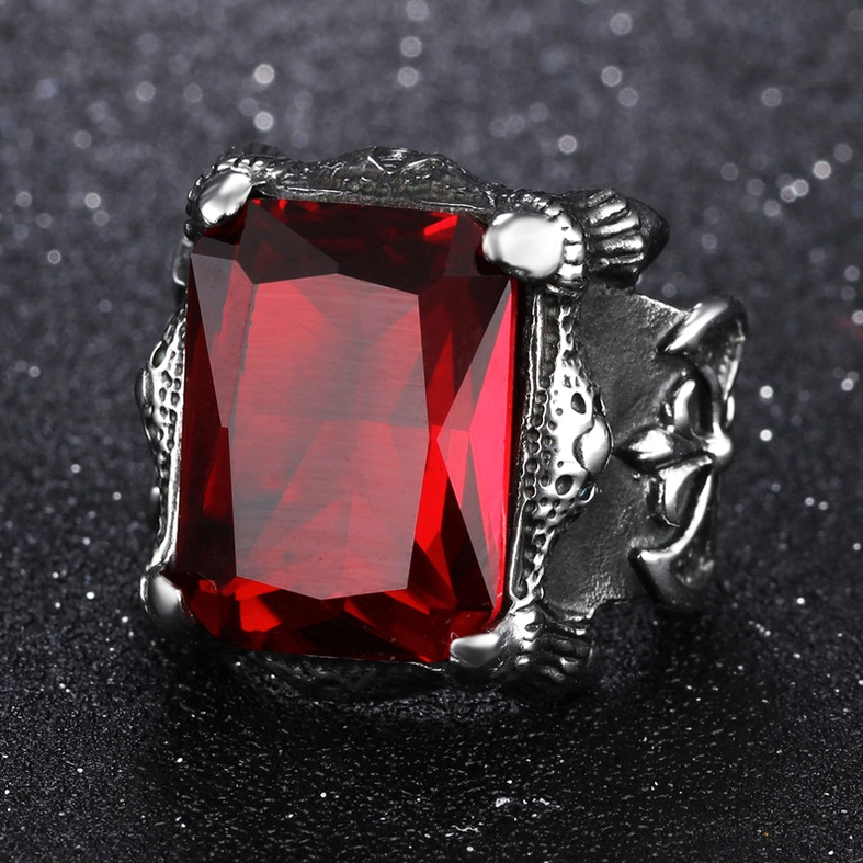 Front-facing close-up of blood red zircon Gothic ring with cross engraving visible on silver-toned metal frame and sparkly background, demonstrating gem brilliance