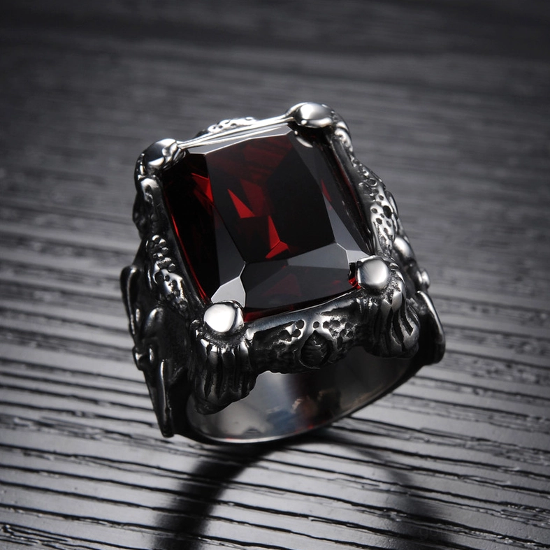 3/4 oblique angle of blood red square zircon ring on dark wood background, showing deep red faceted gemstone and carved Gothic metal band details
