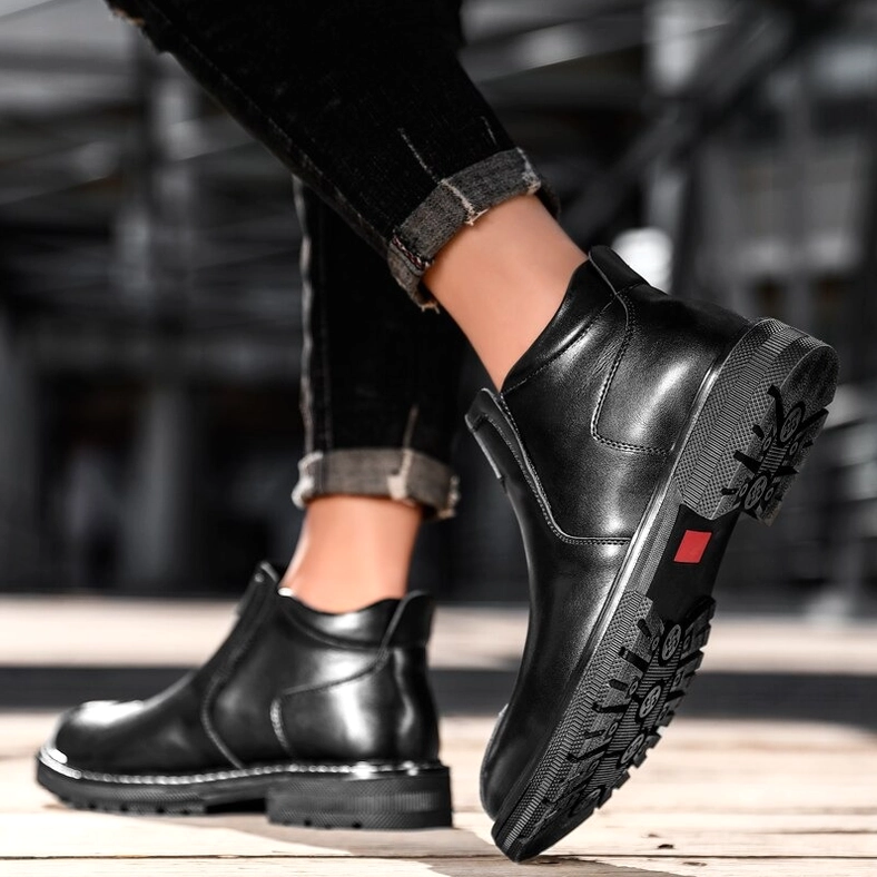 Man displaying black leather gothic ankle boot with textured anti-slip sole, urban outdoor scene