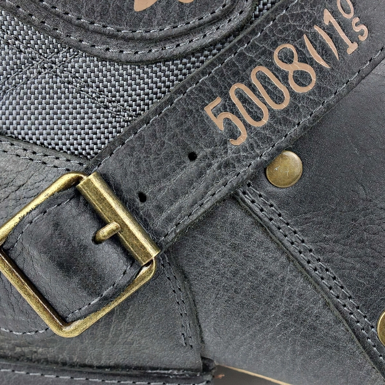 Close-up of antique brass buckle hardware and mixed leather-fabric boot panel detail