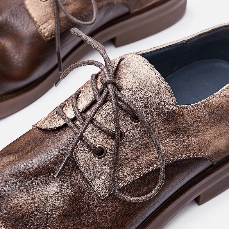 Close-up detail shot of men's distressed leather gothic boots showing two-tone finish, lace-up closure, and leather texture