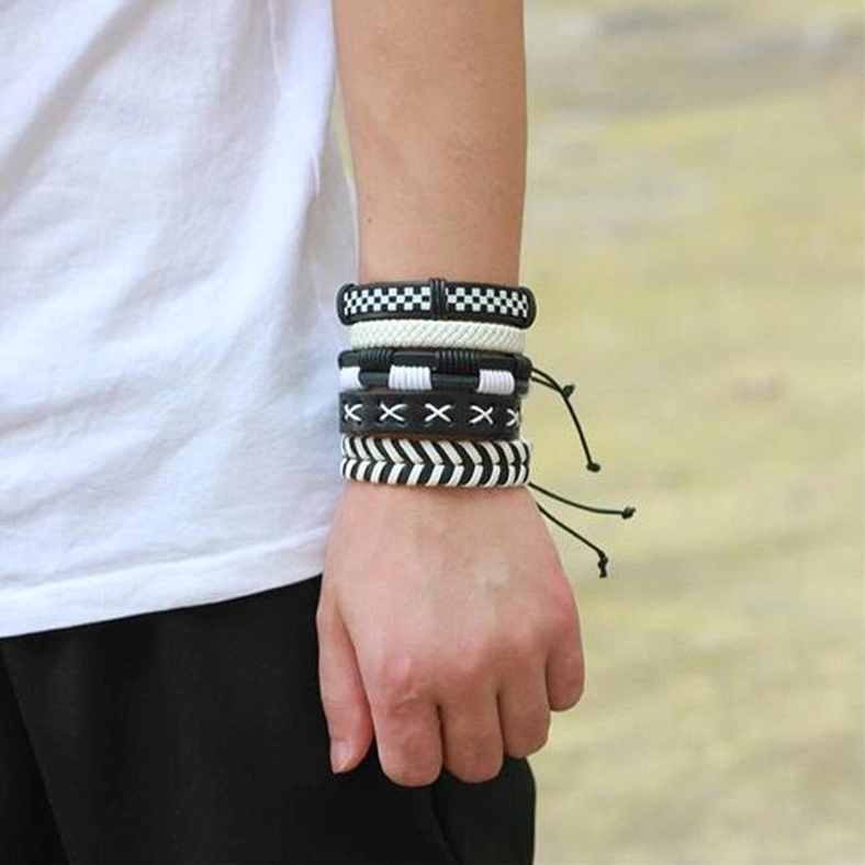 Neatly arranged black and white gothic bracelet set on male model's right wrist - outdoor front view