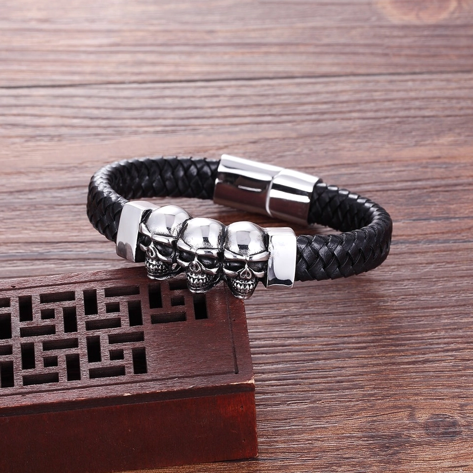 Reverse display of mens skull bracelet showing intricate skull charm details and metalwork from below on rustic wooden background