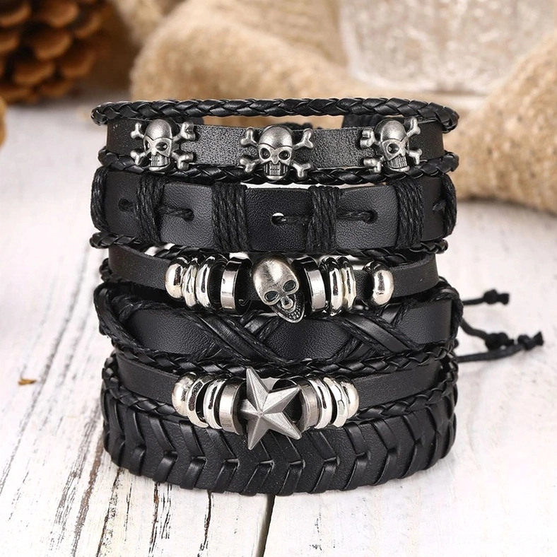 Stacked black gothic skull and star leather bracelets on wooden surface styling