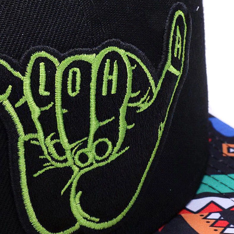 Close-up detail of lime green hand-embroidered shaka hand logo with LOH letters on black cotton twill fabric