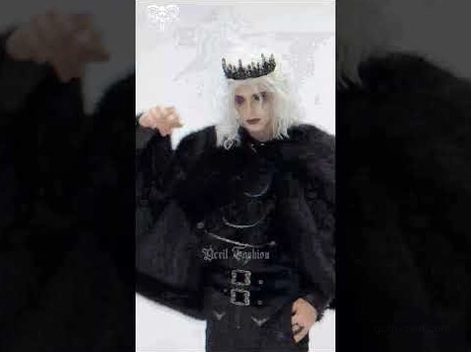 Male model wearing complete black gothic cape costume with crown on dark background, showcasing theatrical goth styling