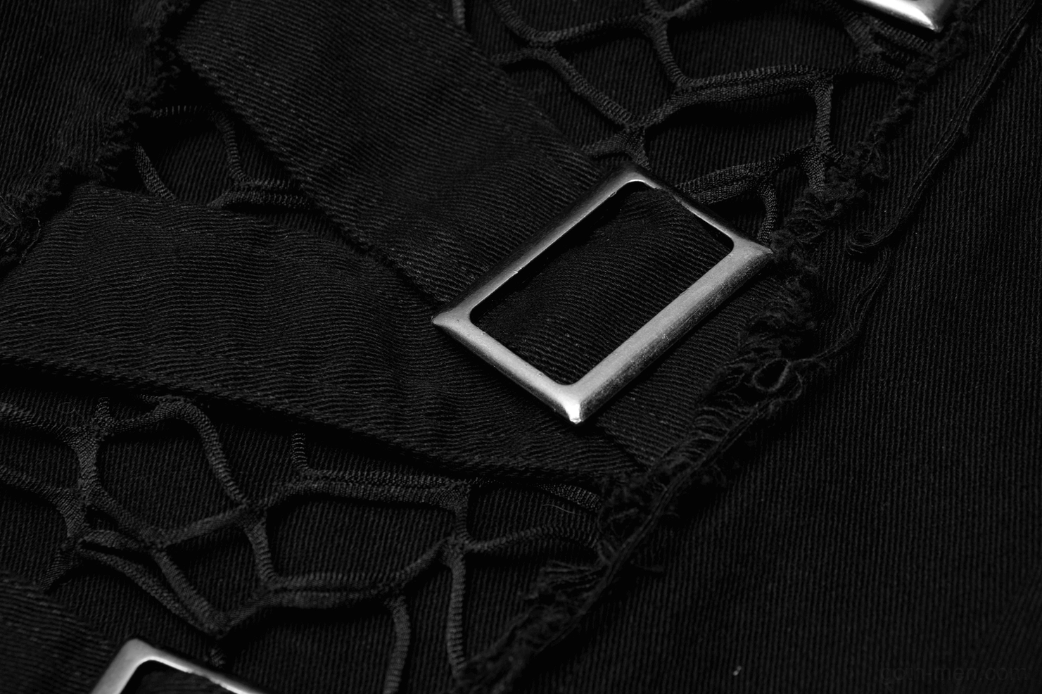 Macro close-up of metal buckle and frayed mesh strapping detail on gothic cargo pants