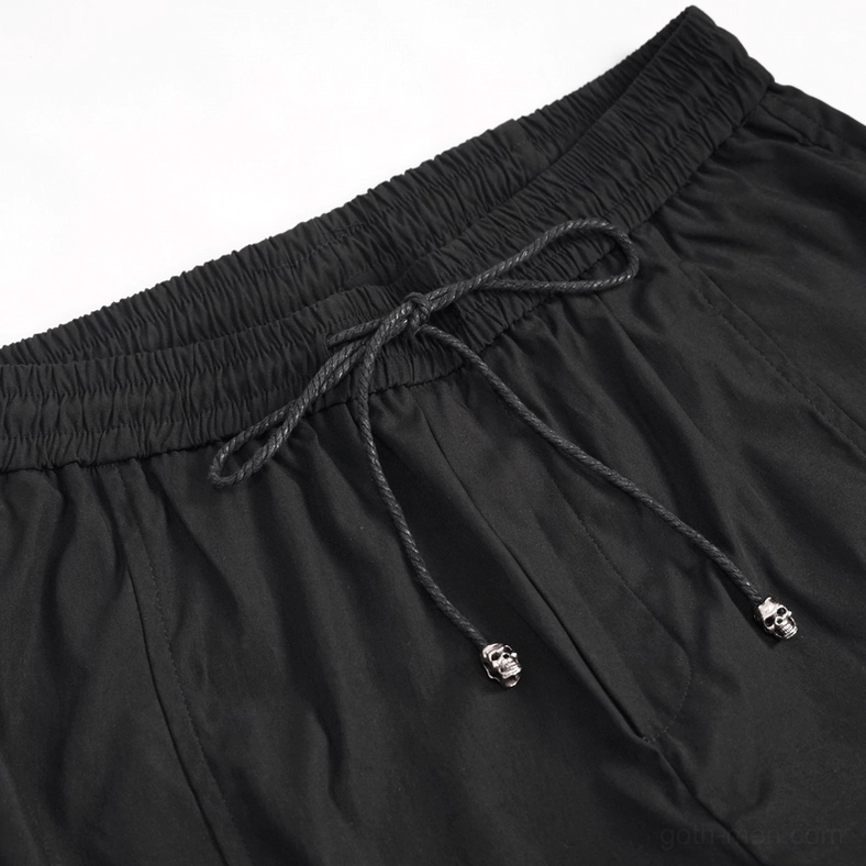 Close-up detail of black gothic cargo pants front waistband featuring braided drawcord with skull charms