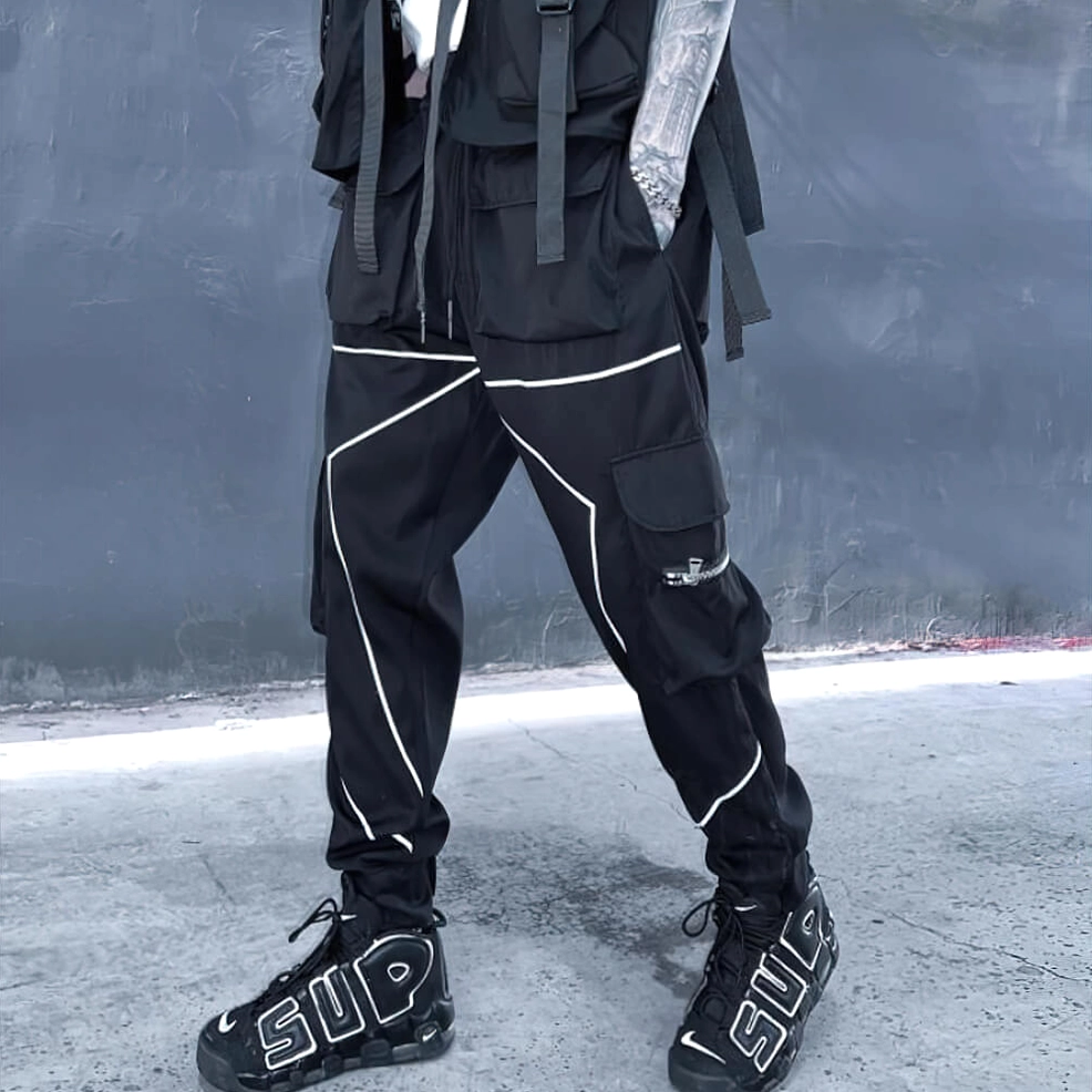 Low angle front view of black cargo pants featuring reflective trim, cargo pockets, and tactical webbing