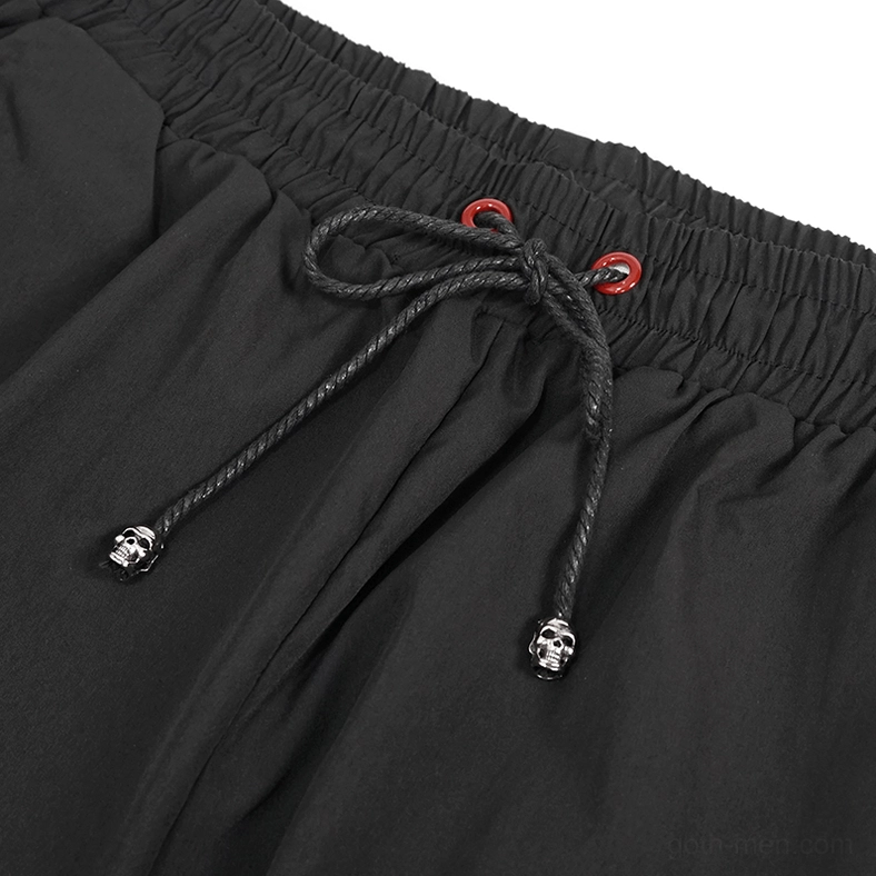 Drawstring detail with skull-shaped ends and red eyelet grommets on gothic cargo pants