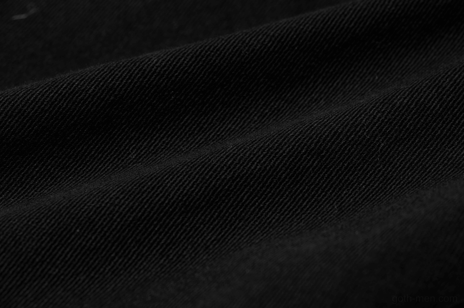 Texture close-up of distressed black twill cotton fabric on gothic cargo pants showing worn finish