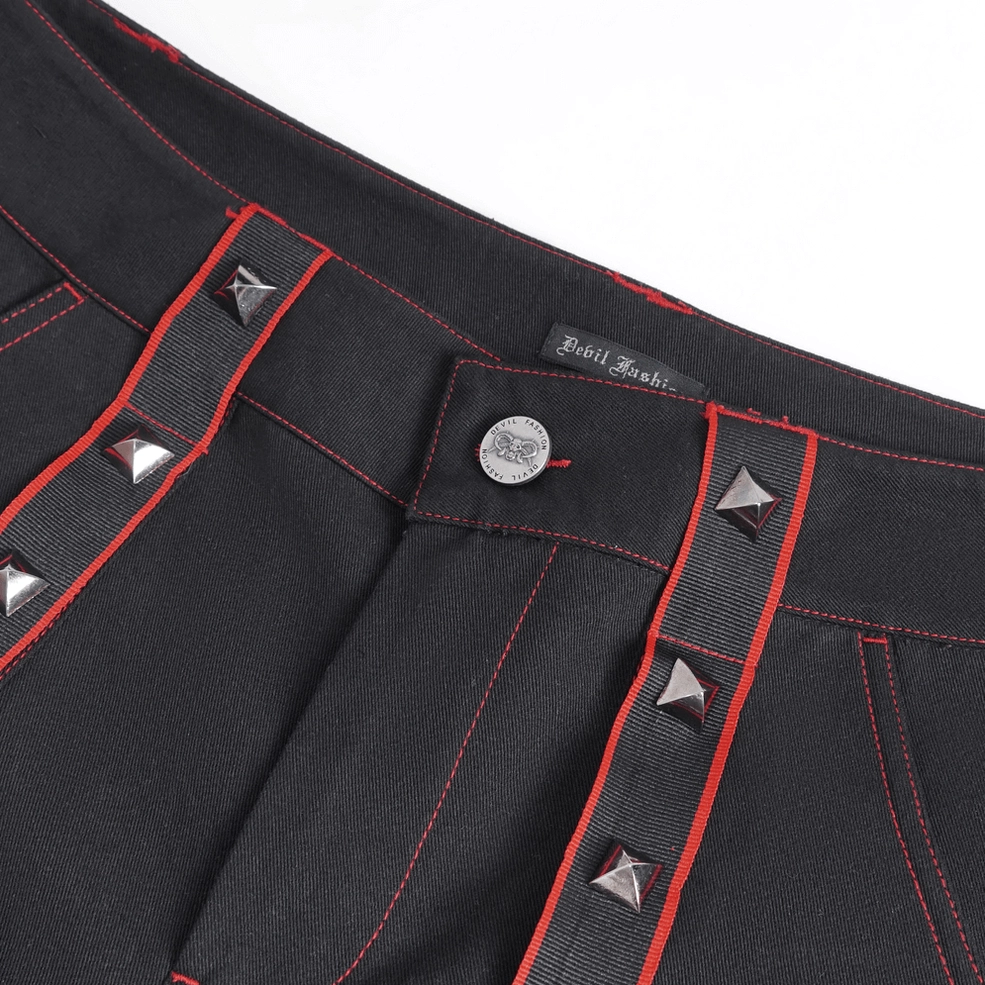 Close-up of gothic cargo pants waistband showing pyramid studs and red webbing trim