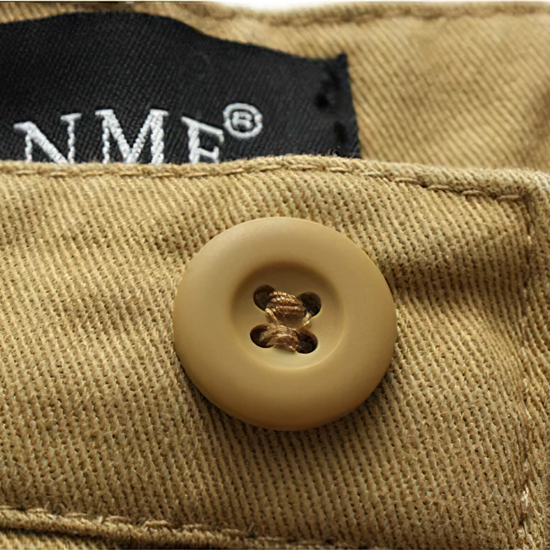 Close-up of khaki twill fabric texture, round button, and clothing label on gothic cargo shorts