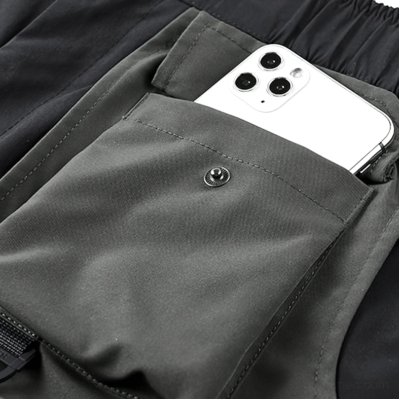 Snap-button cargo pocket detail on black cyberpunk tactical shorts with woven nylon texture