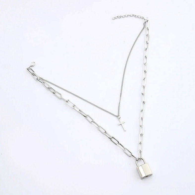 Flat lay overhead view of layered silver gothic chain necklaces with cross and lock pendants