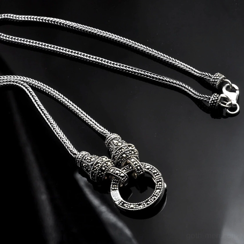 Vintage silver hoop pendant necklace with marcasite decorated clasp on black fabric background, flat lay showing oxidized silver tone