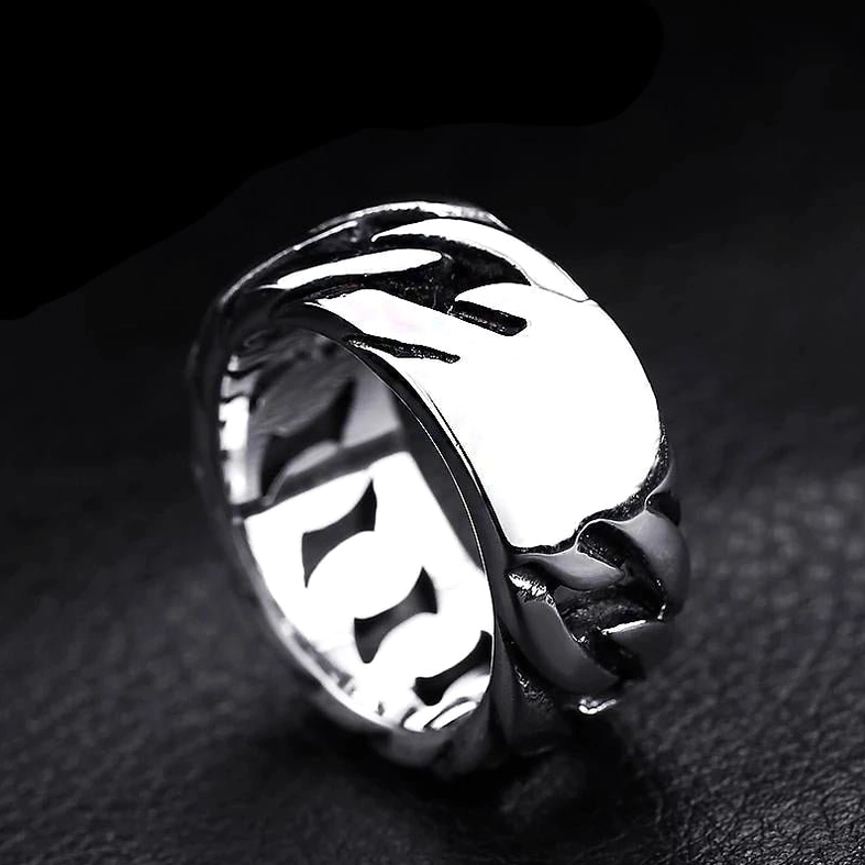 Polished silver gothic chain ring with flat braided surface against dark studio background