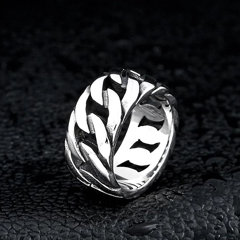 Silver gothic biker chain ring on black leather background with water droplets, detailed side profile