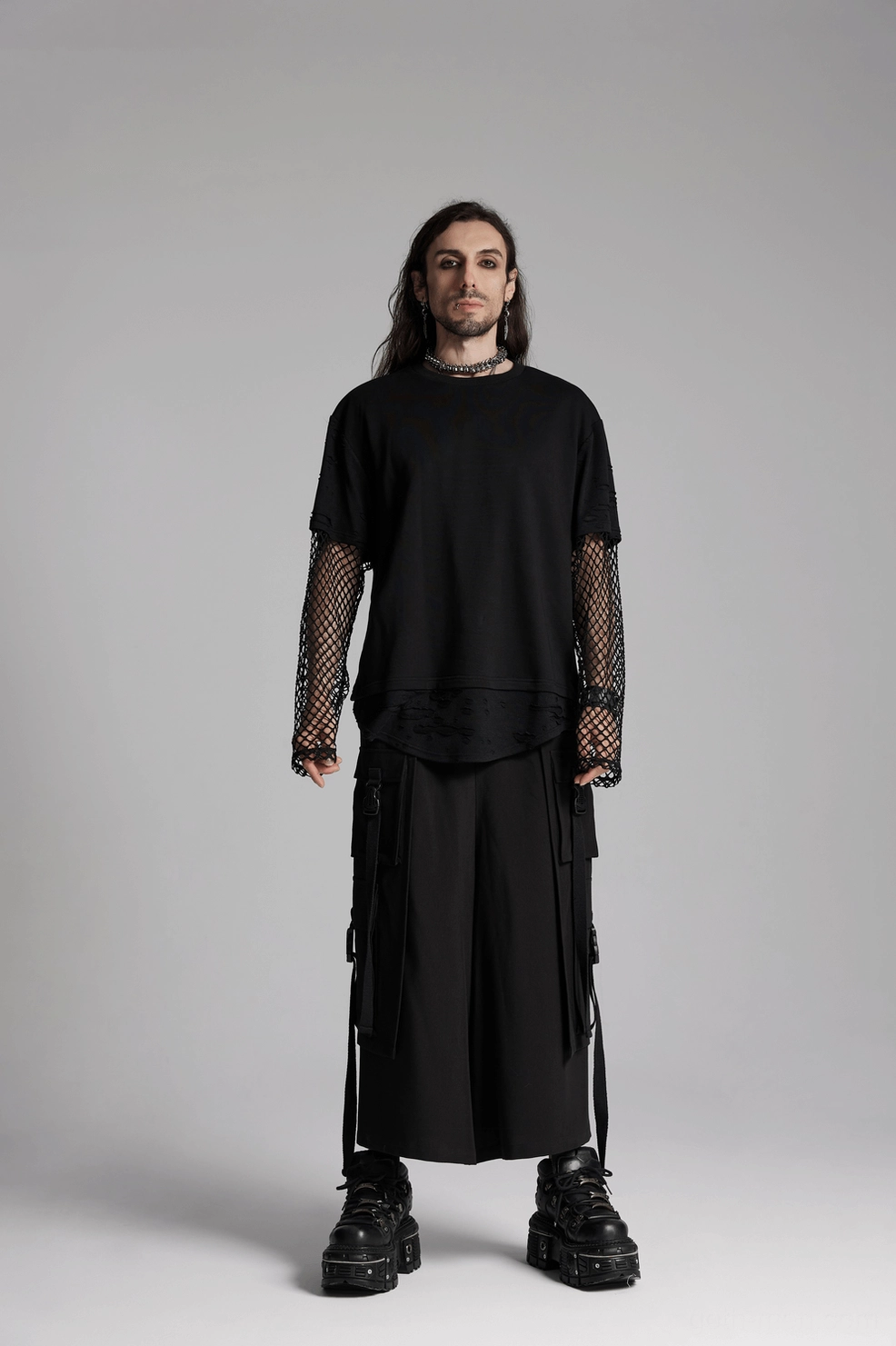 Full-body styling showcase of male model wearing dark-silver spine choker with all-black gothic outfit and chunky platform boots