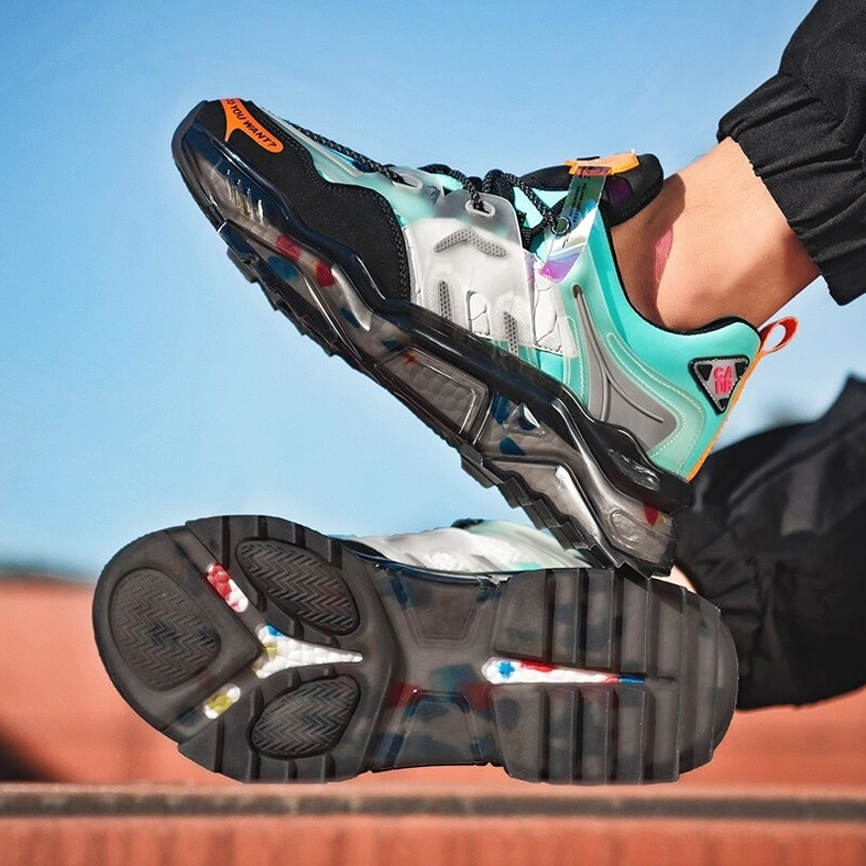 Gothic chunky sneaker worn styling shot showing green fence background and asphalt ground with black pants coordination