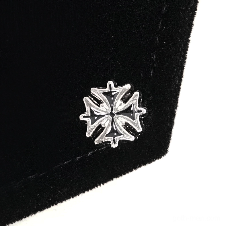 Close-up detail of black velvet fabric texture with silver cross embossed decorative element on gothic cloak