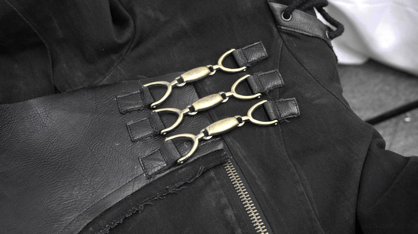 Front shoulder hardware detail of gothic trench coat showing brass-toned metal buckles and leather overlay
