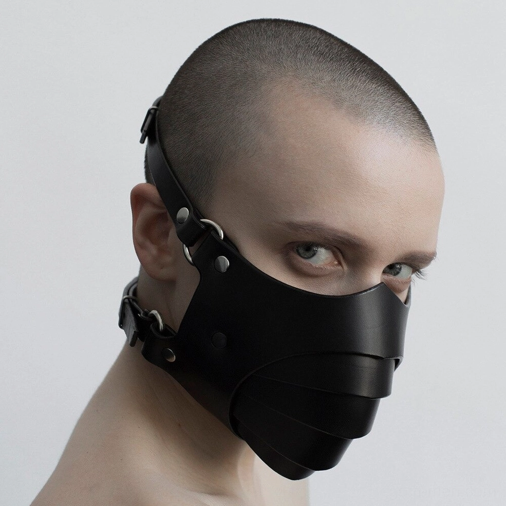 Black gothic cosplay mask fitted on male model, left profile showing layered mouth cover and adjustment straps