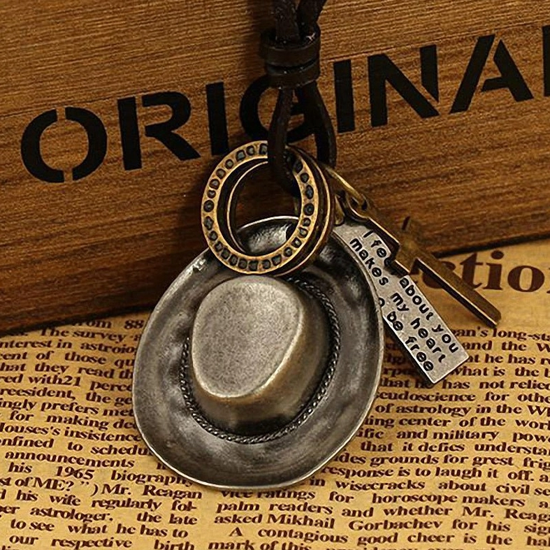 Antique silver-gray cowboy hat pendant on dark vintage background, gothic western aesthetic necklace styling