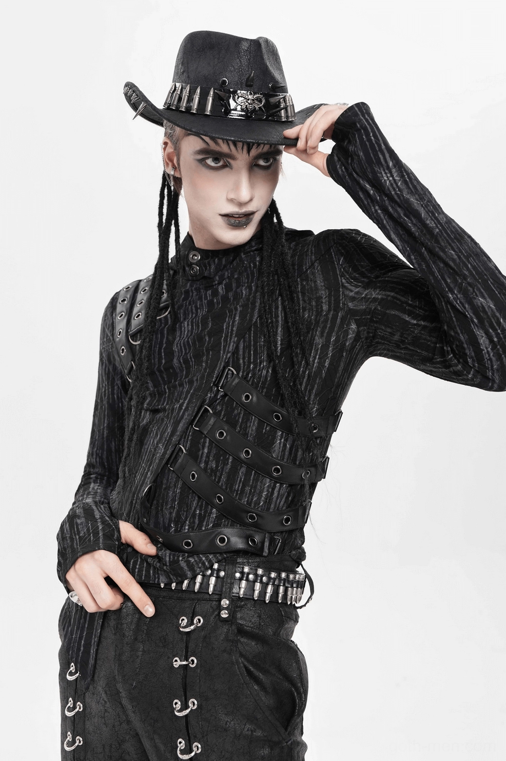 Side profile of black gothic cowboy hat with metal skull and bullet decorations worn by alternative style male model showing band detail