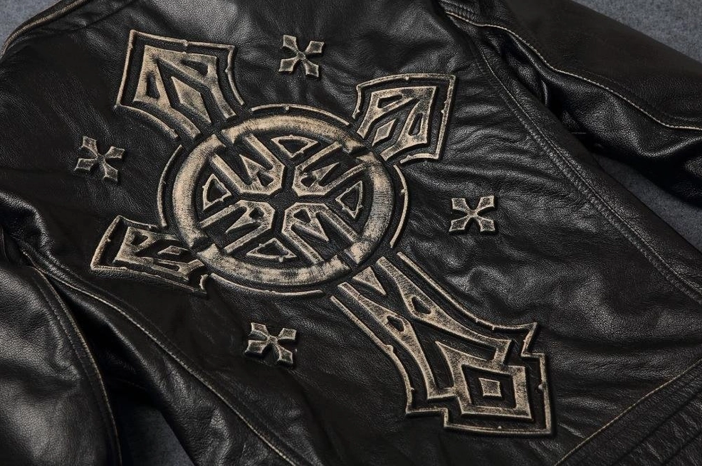 Close-up detail of vintage distressed cross embroidery on black cowhide jacket back