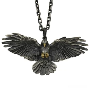 Vintage silver-plated crow raven pendant necklace with golden talons, flat lay front view on black background showing detailed wing feather carvings