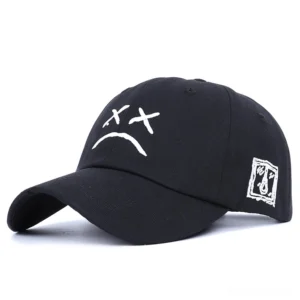 Black gothic crying face baseball cap with embroidered sad XX eyes design, side-front studio view