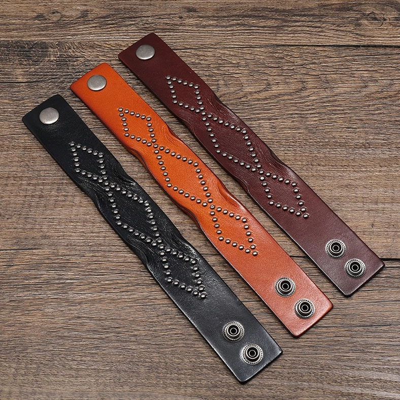 Three color variants of wide leather gothic cuff bracelets arranged flat lay - complete collection view