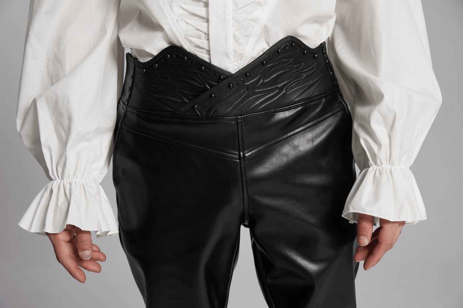 3D curved waistband architectural detail, sculptural stud arrangement on black glossy PU leather surface