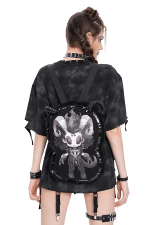Female model wearing black gothic demon plush backpack with spiral horns and spike trims against white studio background, full back view showcasing monochromatic demon print design