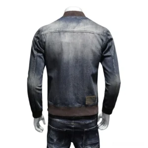 Vintage washed denim bomber jacket back view showing embossed leather brand patch and brown ribbed hem detail