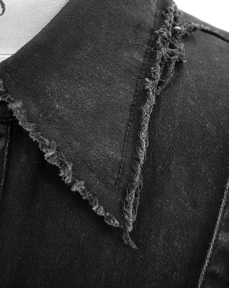 Detailed view of frayed raw denim edge and dark black washed fabric of gothic vest