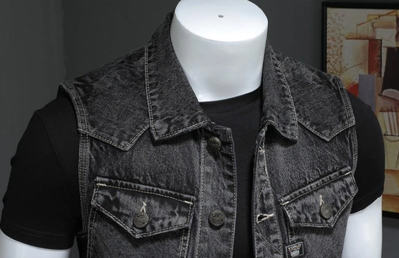 Close-up front detail of gothic denim vest showing pointed collar, branded metal buttons, and chest pocket construction