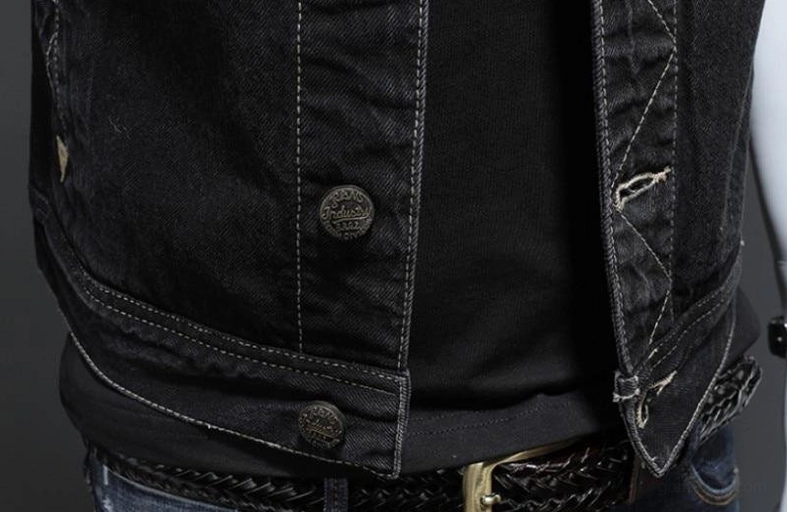 Lower section of black denim vest showing button closure at waist hem and authentic faded denim texture