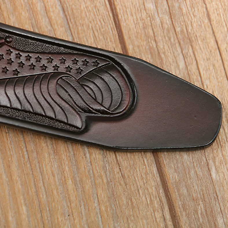 Gothic eagle belt tail with embossed star and wave motifs - dark brown leather close-up