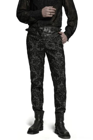 Front three-quarter view of black gothic embroidered lace slim-fit pants with leather waist strap on male model
